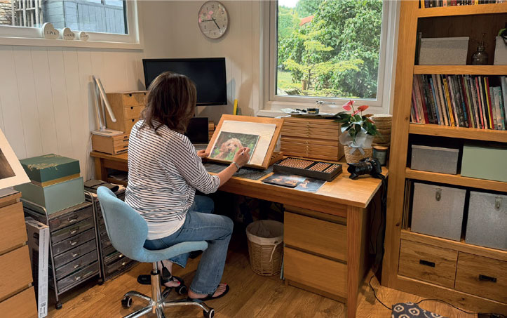 Diane Spencer, an artist living in the village of Higham, Derbyshiren sat at her desk in her new garden room