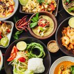 Delicious looking Thai foods on a black cloth table top.