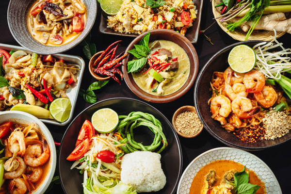 Delicious looking Thai foods on a black cloth table top.
