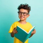 Photo of intelligent schoolboy with brown hair dressed yellow t-shirt holding book look empty space isolated on turquoise color background.
