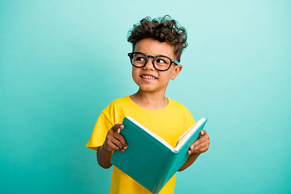 Photo of intelligent schoolboy with brown hair dressed yellow t-shirt holding book look empty space isolated on turquoise color background.