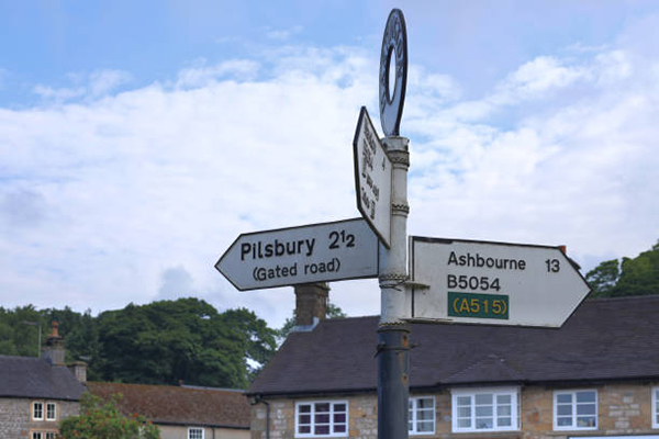 Summer 2021, Hartington, Peak District, Derbyshire, England, UK - A signpost in the village of Hartington shows the road direction to the Peak District towns of Pilsbury and Ashbourne