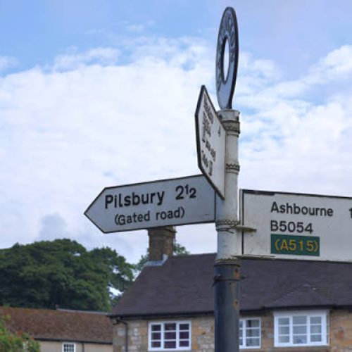 Summer 2021, Hartington, Peak District, Derbyshire, England, UK - A signpost in the village of Hartington shows the road direction to the Peak District towns of Pilsbury and Ashbourne