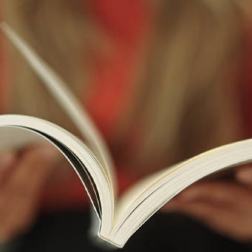 Close-up hand of woman reading and open book page.