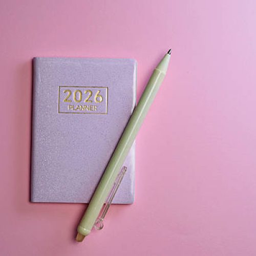 2026 small planner and pen against pink background.